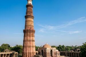 Towering red sandstone Qutub Minar monument against a blue sky in Delhi